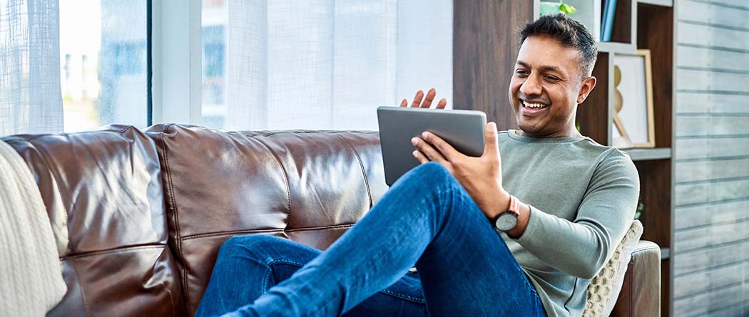 Person lounging on a couch using a tablet.